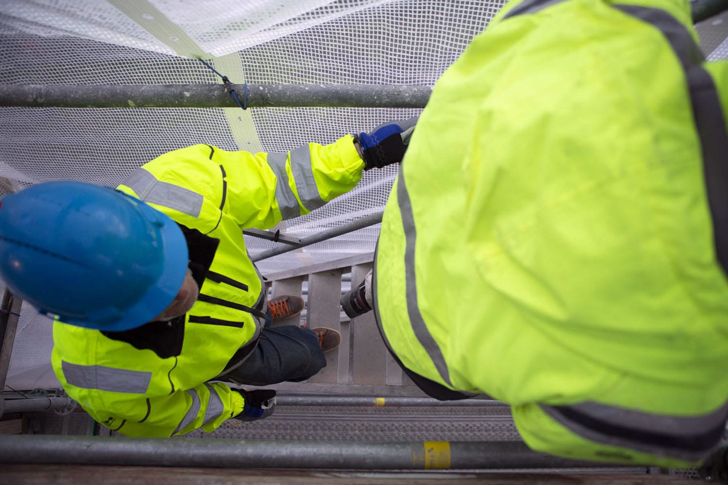 Ställningsbyggare i varseljackor går uppför trappa. Foto: Martin Modigh Karlsson